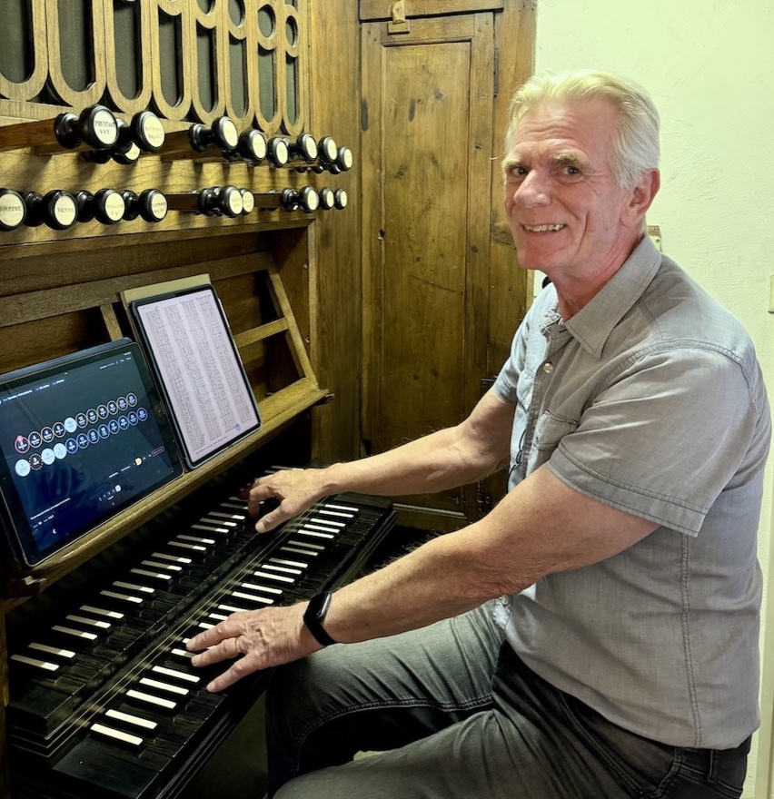 Hans Latour aan de speeltafel van de Sint-Lambertus in Rosmalen,
                  met een tablet en een uitgedraaide lijst op de lessenaar.